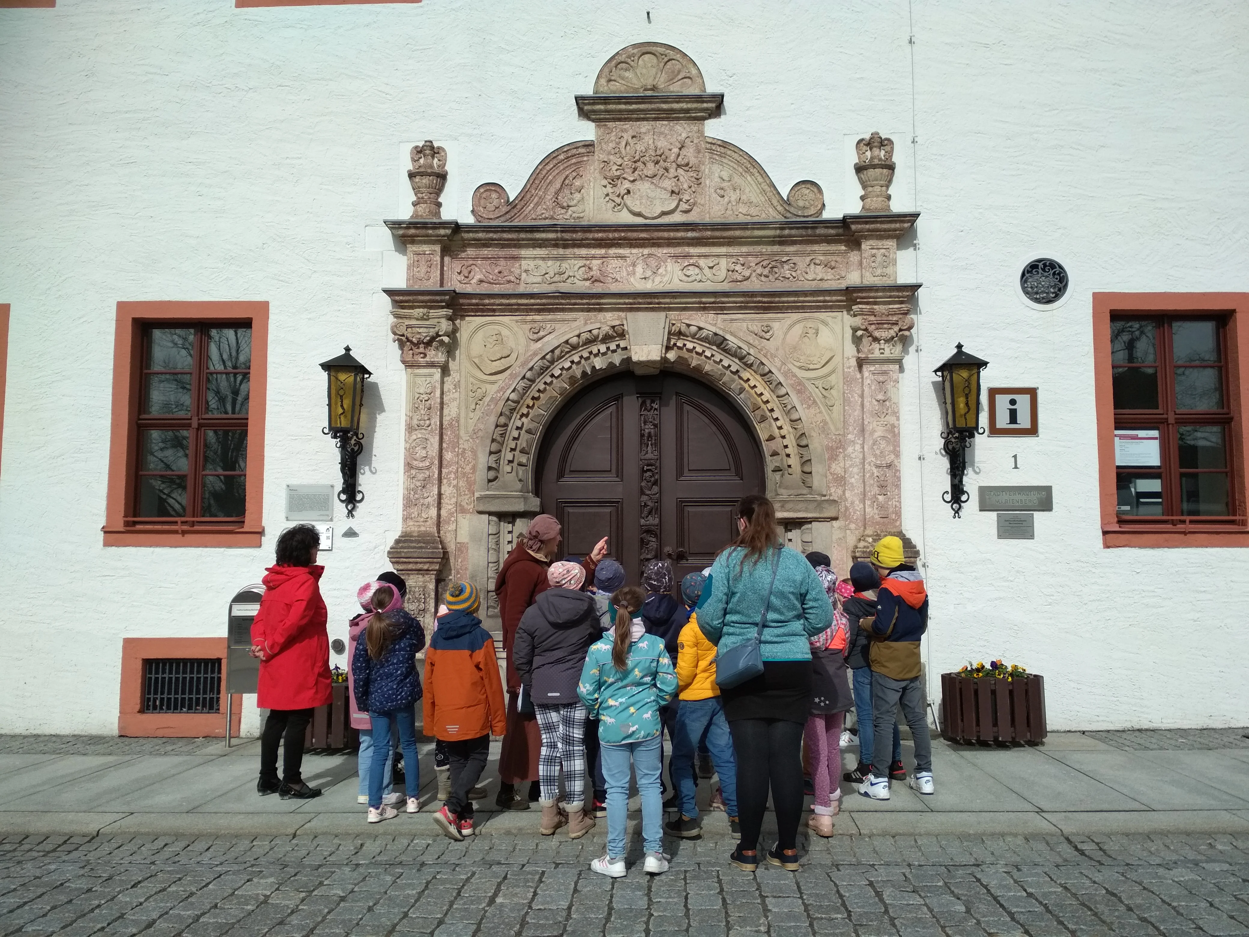 Eine Schulklasse betrachtet das Marienberger Rathausportal.