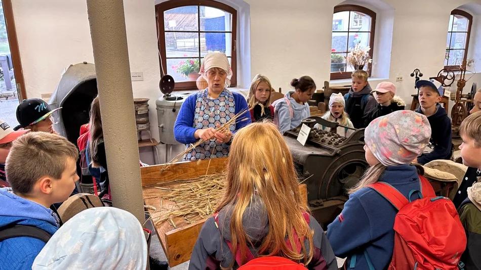 In der historischen Böttcherfabrik gibt es viel zu entdecken: Landwirtschaftsgeräte, Maschinenbauwerkstatt und Landschaftsbilder. Eine Kindergruppe lauscht den Ausführungen zur Fabrikgeschichte, die von einer erwachsenen Person erklärt wird.