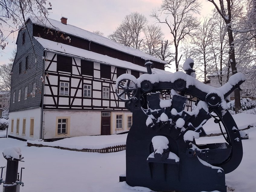 Das Foto zeigt eine Außenansicht der winterlich eingeschneiten Papiermühle Niederzwönitz.
