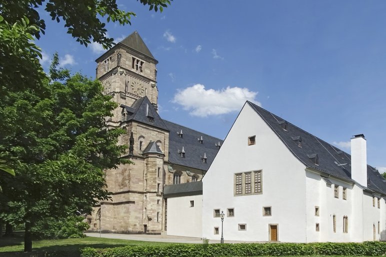 Das Foto zeigt eine sommerliche Außenansicht des in historischen Kloster- und Schlossgebäuden untergebrachten Schloßbergmuseums mit der sich anschließenden Schloßkirche. Im Vordergrund ist eine grüne Parkfläche zu sehen.