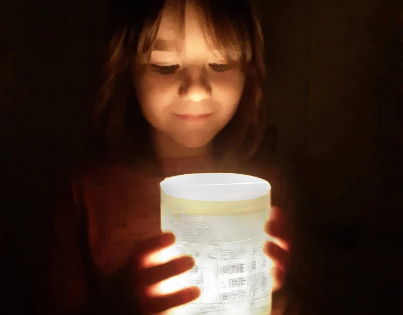 Ein leuchtendes Souvenir für daheim. Ein Mädchen (circa 7 Jahre) blickt auf ein selbst gebasteltes Windlicht, auf dem Schloss Hartenfels abgebildet ist.