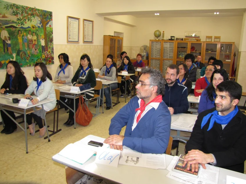 Unterrichtszimmer im historischen Klassenzimmer DDR-Schule Das Foto zeigt ein mit erwachsenen Besucherinnen und Besuchern voll besetztes Klassenzimmer aus der DDR-Zeit, die Gäste tragen blaue und rote Pionierhalstücher.