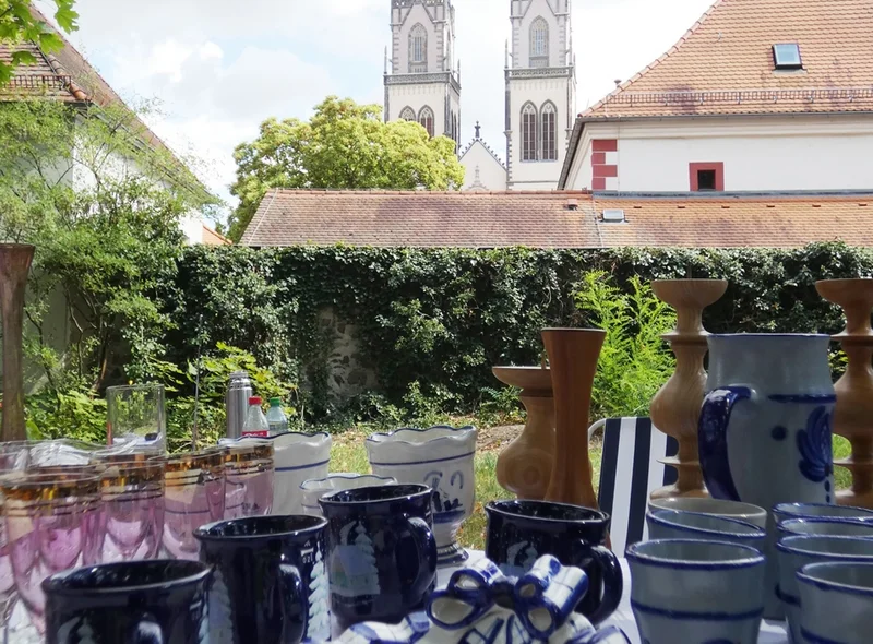 Keramik und Gläser auf einem Tisch im Freien, im Hintergrund die zwei Türme der Oschatzer Stadt- und Pfarrkirche St. Aegidien