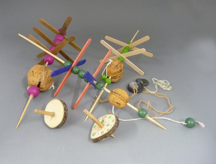 Foto von Knopf-Jojos, Kreiseln und Nussmühlen, die aus Holzstäbchen und Holzscheiben, Holzperlen, Walnüssen und Stoff-Fäden gebastelt wurden