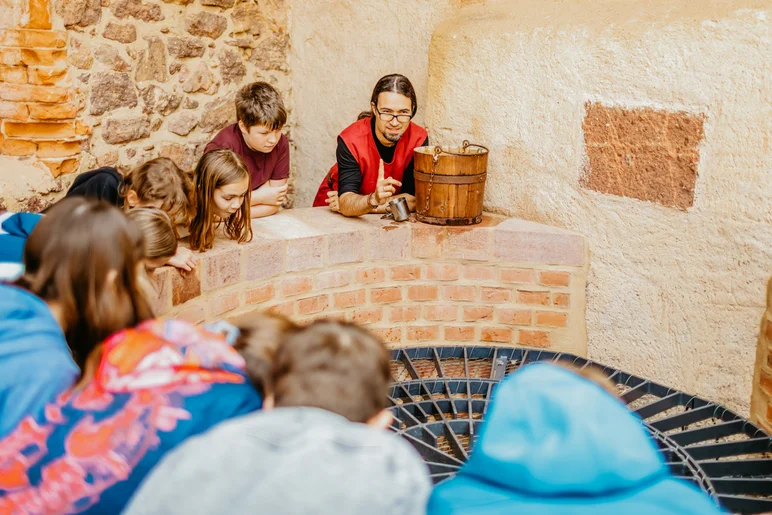 Schülergruppe beim Blick in den Brunnenschacht des Burgbrunnens.
