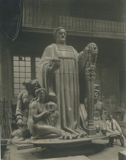 Historisches Schwarzweiß-Foto des monumentalen Richard-Wagner-Denkmals, das gerade in der Werkstatt gegossen wird. Am Rand sitzt ein Mann, wodurch ein Größenvergleich möglich wird.