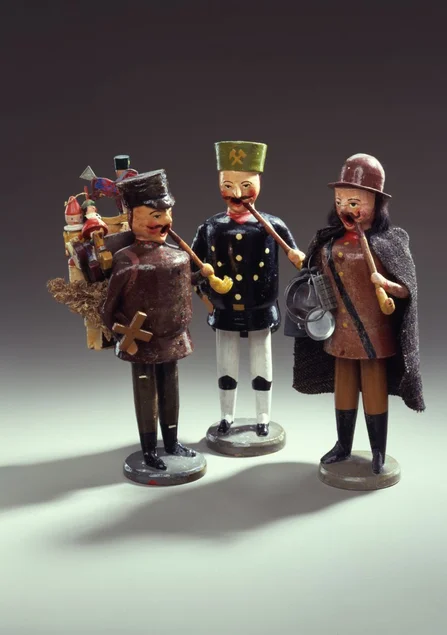 Drei geschnitzte und bemalte Holzfiguren, die im Stil historischer Handwerke beziehungsweise Zünfte gekleidet sind