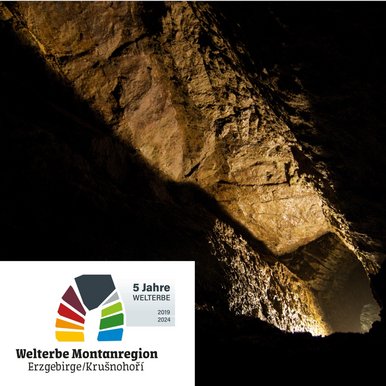 UNESCO-Welterbetag im Erzgebirgsmuseum Das Foto gibt den Blick frei in einen beleuchteten Bergwerksstollen. Unten links die Aufschrift "5 Jahre Welterbe Montanregion Erzgebirge/Krušnohoří, 2019 bis 2024".