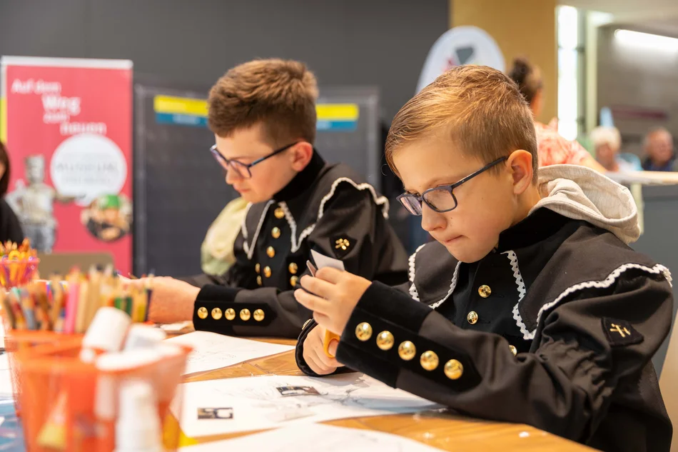 Bastelaktion im Museum Zwei Jungen in Bergmannsuniformen basteln und malen konzentriert an einem Tisch.