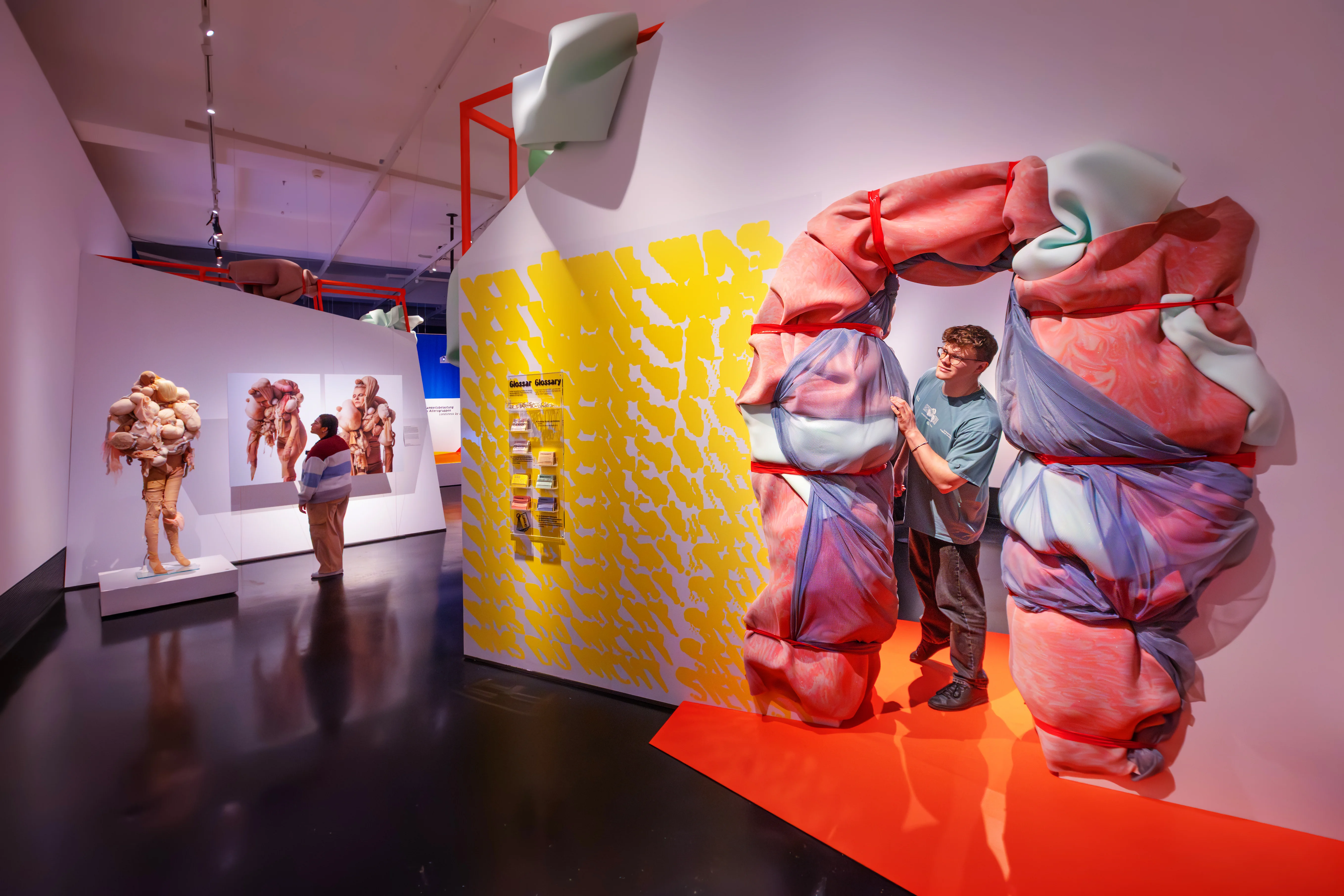 Eine junger Mann schaut aus einem Ausstellungsraum, der wie eingeschnürt aussieht.