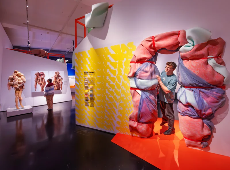 Eine junger Mann schaut aus einem Ausstellungsraum, der wie eingeschnürt aussieht.