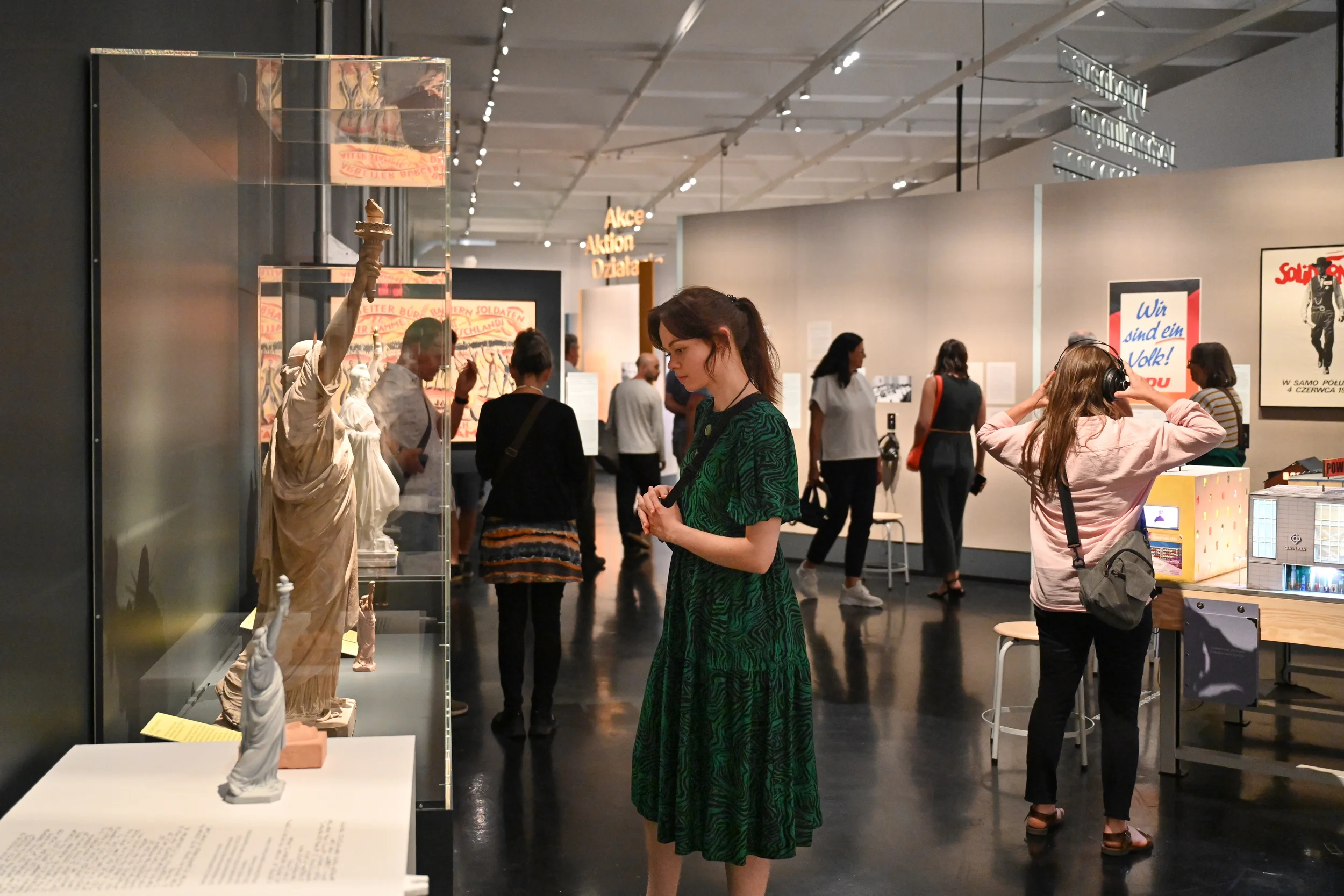Eine Besucherin betrachtet ein Modell der Freiheitsstatue. Im Hintergrund schauen sich Menschen weitere Exponate an.