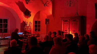 In warmes, rotes Licht getauchtes Publikum beim einem Konzert von Friedbert Wissmann im Festsaal im Schloss Hinterglauchau