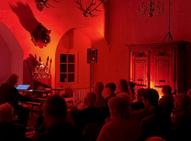 In warmes, rotes Licht getauchtes Publikum beim einem Konzert von Friedbert Wissmann im Festsaal im Schloss Hinterglauchau