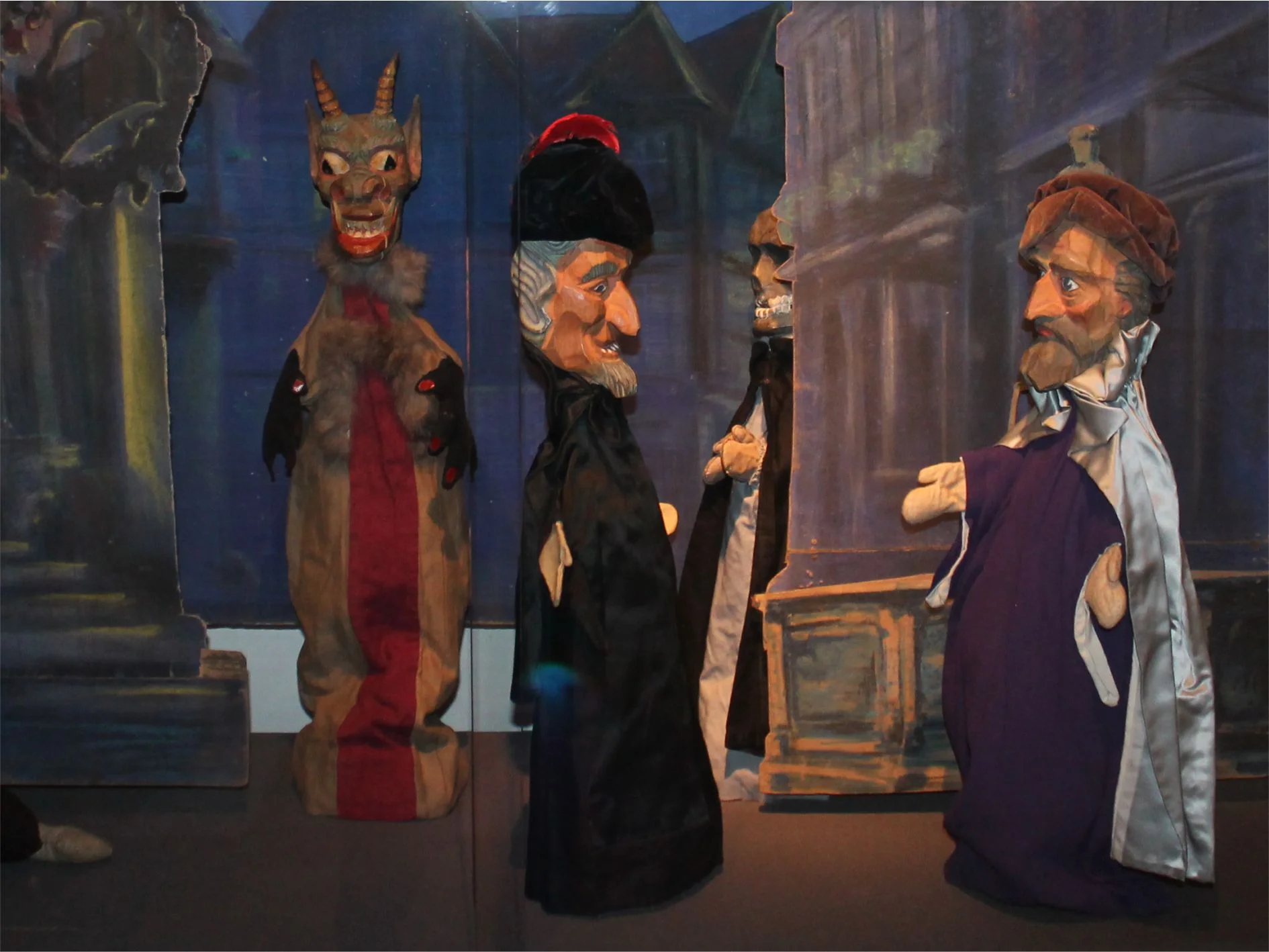 Puppentheaterszene mit vier Handpuppen, darunter die Figuren des Faust und des Mephisto