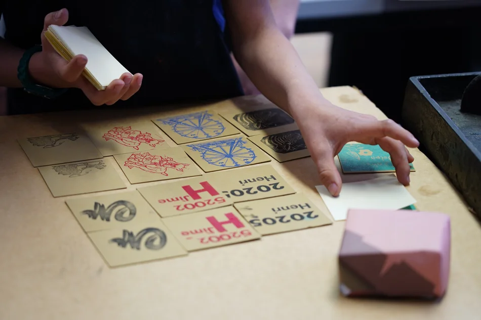 Gedrucktes Memory Zwei Hände decken mehrere quadratische, mit unterschiedlichen Motiv-Paaren bedruckte Kärtchen um.