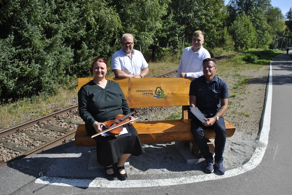Auf einer Bank am Chemnitztalradweg sitzen eine Violinistin und drei weitere Musiker.