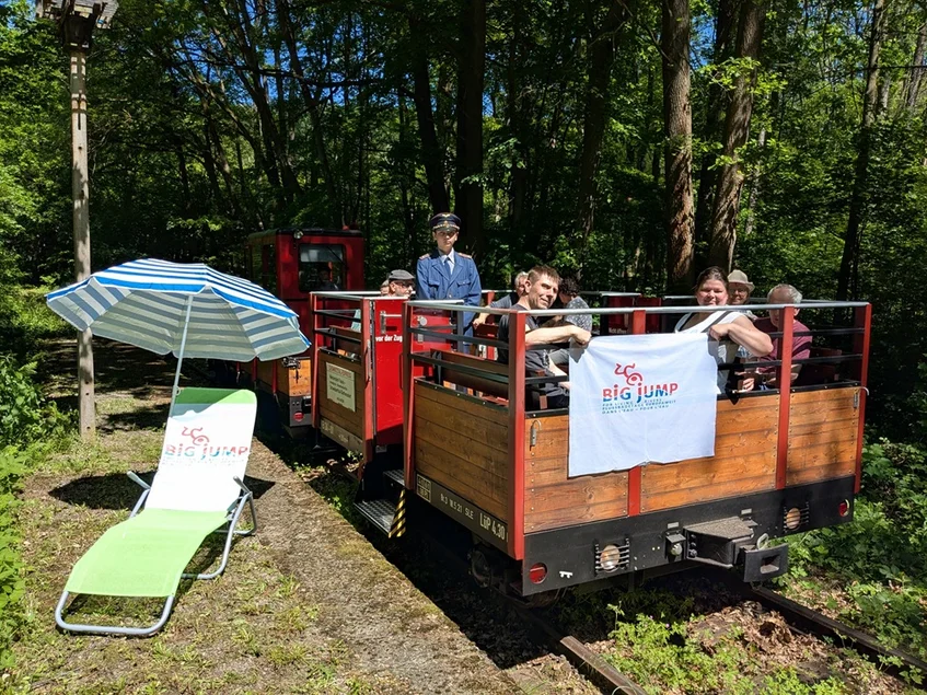 Ein Zug der Chemnitztalbahn am Haltepunkt Amselgrund, an welchem Sonnenliege und Sonnenschirm auf Besucher warten.