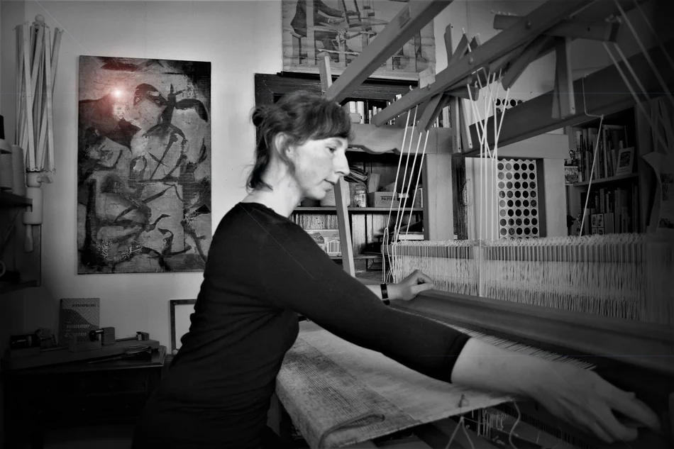 Danjana Brandes am Webstuhl Eine Frau sitzt an einem Webstuhl und webt Stoff für Bilder.