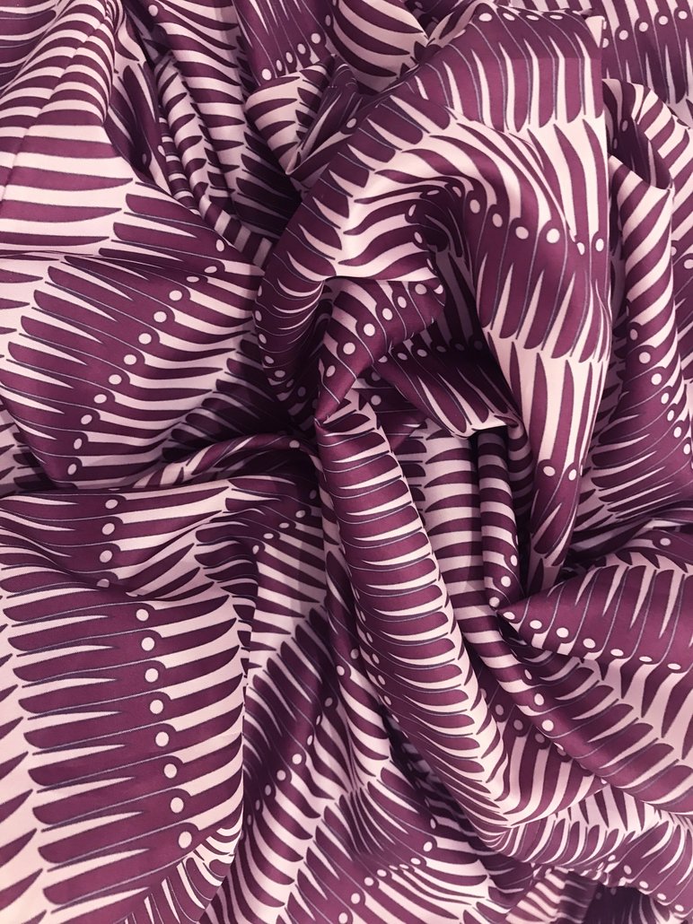 Traditionell anmutendes Tuch, dessen in Violett auf Rosa gedrucktes Muster sich bei genauer Betrachtung als Aneinanderreihung von Klappmessern herausstellt