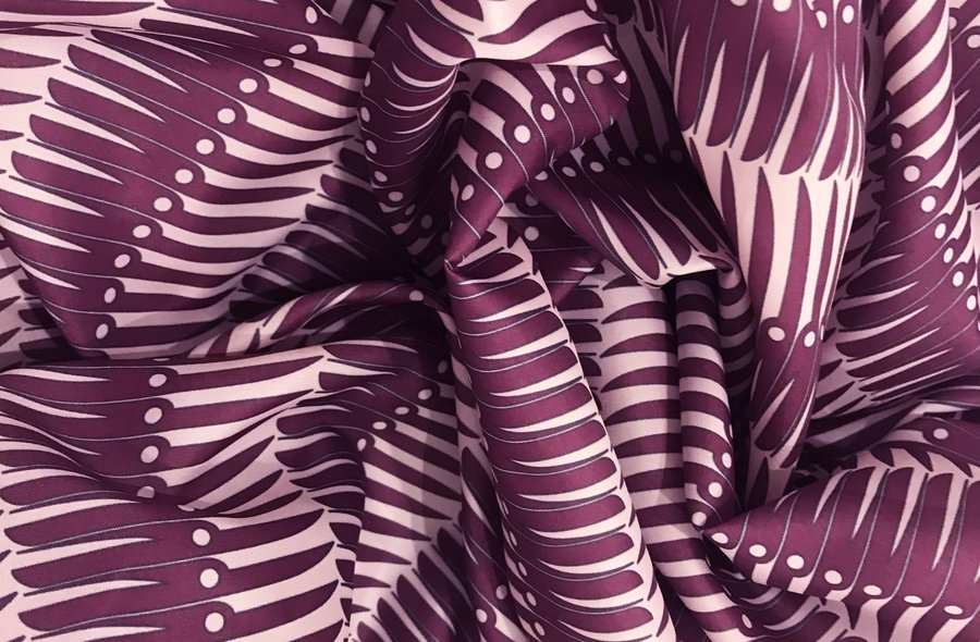 Traditionell anmutendes Tuch, dessen in Violett auf Rosa gedrucktes Muster sich bei genauer Betrachtung als Aneinanderreihung von Klappmessern herausstellt