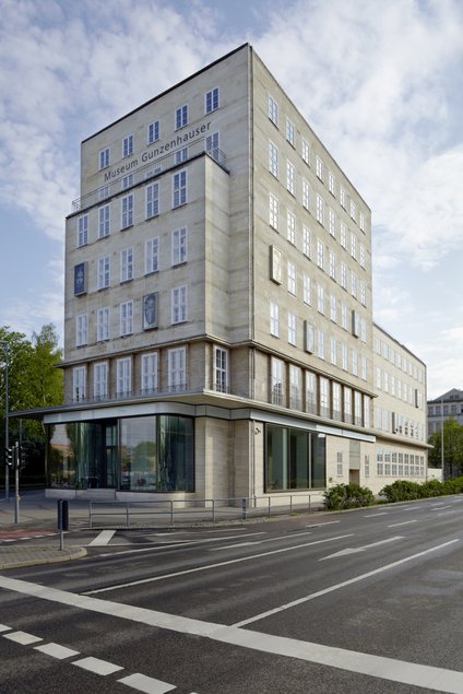 Das Bild zeigt eine Außenansicht des imposanten, siebenstöckigen Gebäudes des Museum Gunzenhauser, das sich über die mehrspurige Zwickauer Straße in Chemnitz erhebt. Das Museum ist in einem ehemaligen Sparkassengebäude untergebracht, welches 1928 bis 1930 im Stil der Neuen Sachlichkeit erbaut wurde.
