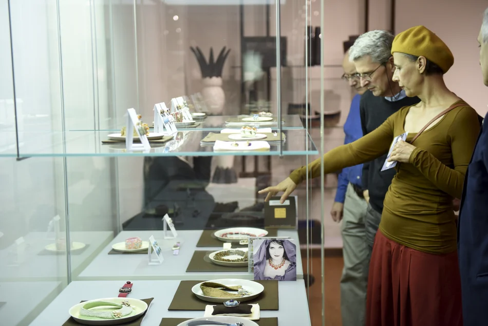 Besucher der Grassimesse Personen in einer Kunstmesse stehen vor Vitrinen und betrachten die darin ausgestellten Objekte.