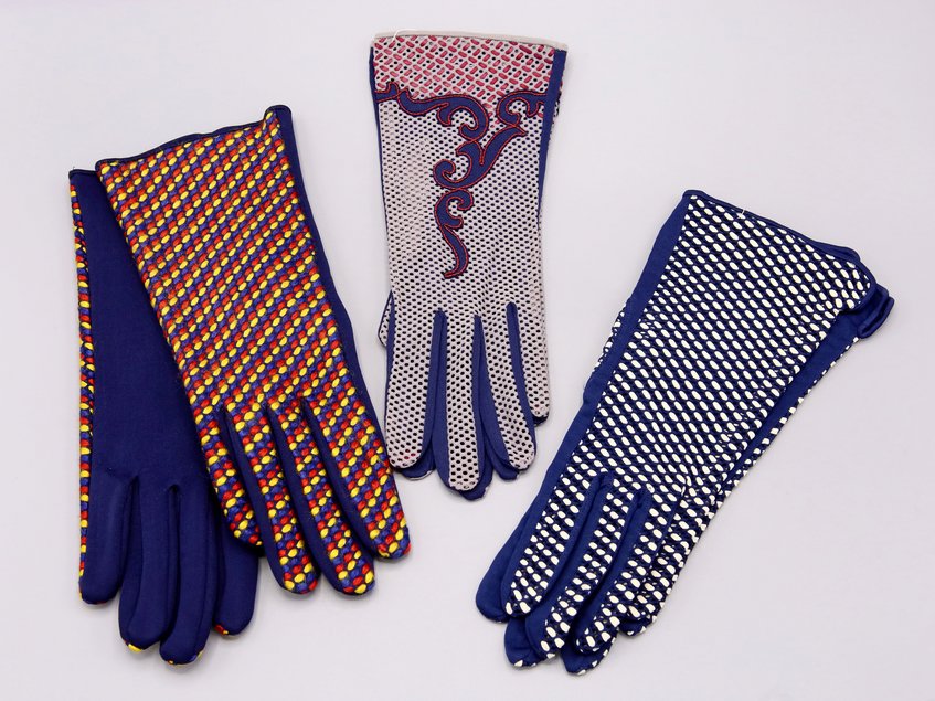 Das Foto zeigt zwei Paar Handschuhe aus der Sammlung des Esche-Museums. Beide Paare weisen farbige Ornamente auf dunkelblauem Grund auf.