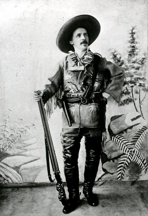 Karl May als Old Shatterhand 1896 Historisches Foto von Karl May, wie er im Old-Shatterhand-Kostüm vor der Kamera mit Gewehr, Lederjacke und Hut posiert