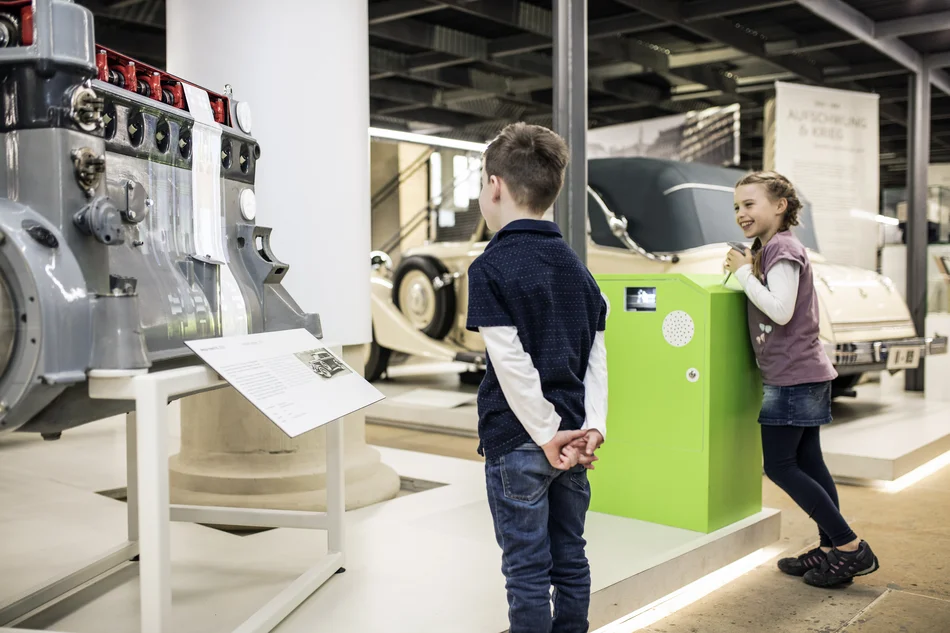 Kinder an einer Projektion eines 4-Takt-Motors Kinder an einem Gaspedal, das die Projektion eines 4-Takt-Motors in Bewegung versetzt