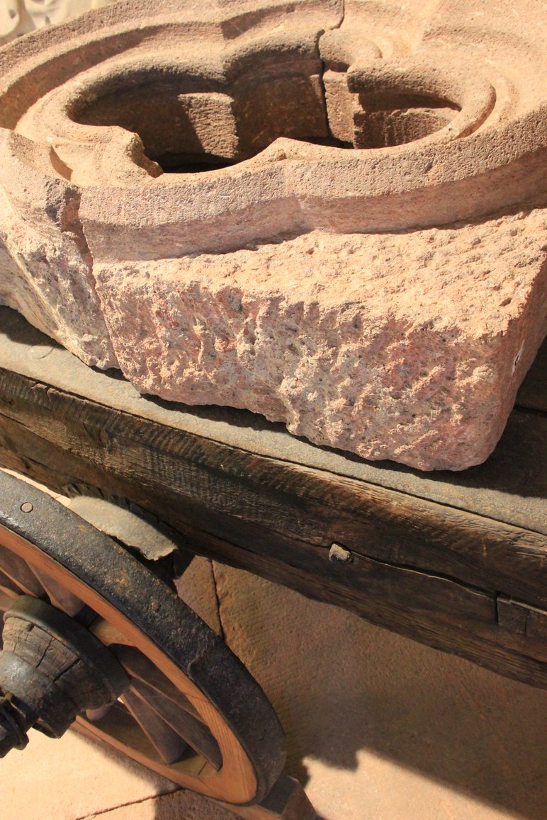 Foto eines auf einer Holzkarre liegenden historischen Mauerwerk-Elements aus rötlichem Porphyrgestein