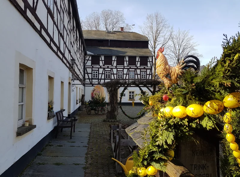 Geschmückter Osterbrunnen an der Papiermühle Niederzwönitz, einem großen historischen Fachwerkgebäude