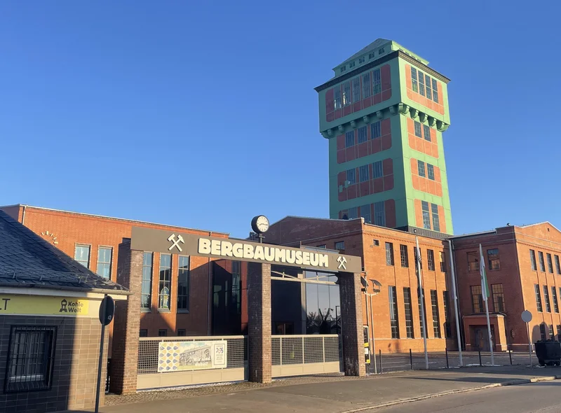 Historische Schachtanlage mit Förderturm und prägnantem Eingangstor. Über dem Tor steht "Bergbaumuseum".