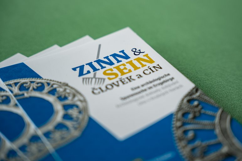 Detailaufnahme dreier aufgefächerter Flyer mit dem Titel "Zinn und Sein"