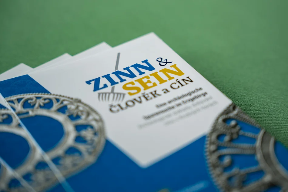 Detailaufnahme dreier aufgefächerter Flyer mit dem Titel "Zinn und Sein"