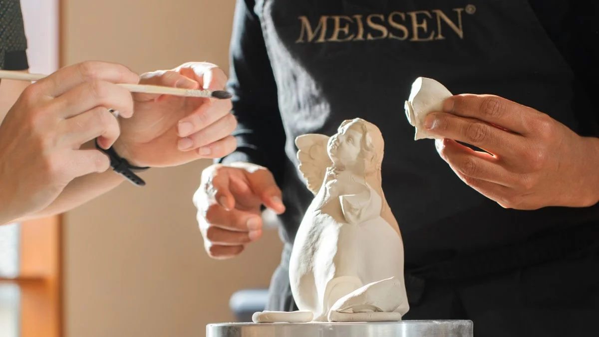 Kreativ-Workshop Engel Im Kreativ-Workshop bei MEISSEN gestalten Hände mit feinen Werkzeugen eine Porzellan-Engelsfigur – konzentrierte Atmosphäre.