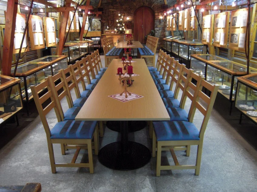 Knappschaftssaal Zentral im langgestreckten Saal stehen zwei lange Tafeln mit Stühlen an beiden Seiten, entlang der Wände befinden sich Vitrinen und Bildtafeln.