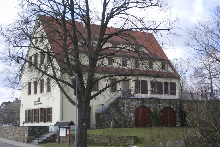 Das Museum in Brand-Erbisdorf ist ein 3-stöckiges älteres Gebäude mit Natursteinsockel, Spitzdach und begrüntem Außenbereich.