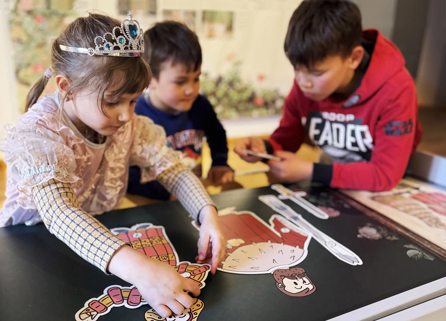 Drei Kinder sind über einen Tisch gebeugt und lösen ein Rätsel.