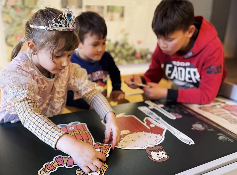 Drei Kinder sind über einen Tisch gebeugt und lösen ein Rätsel.