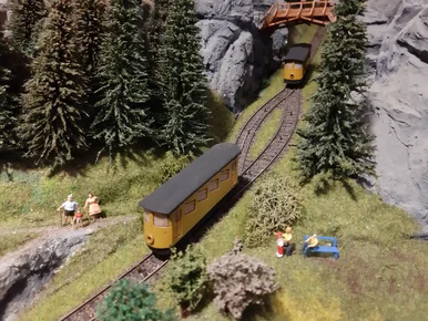 Drahtseilbahn auf der Schauanlage Nahaufnahme eines Teiles eines großen Modelleisenbahn, auf der eine Drahtseilbahn sich ihre Weg durch bewaldete Landschaft bahnt.