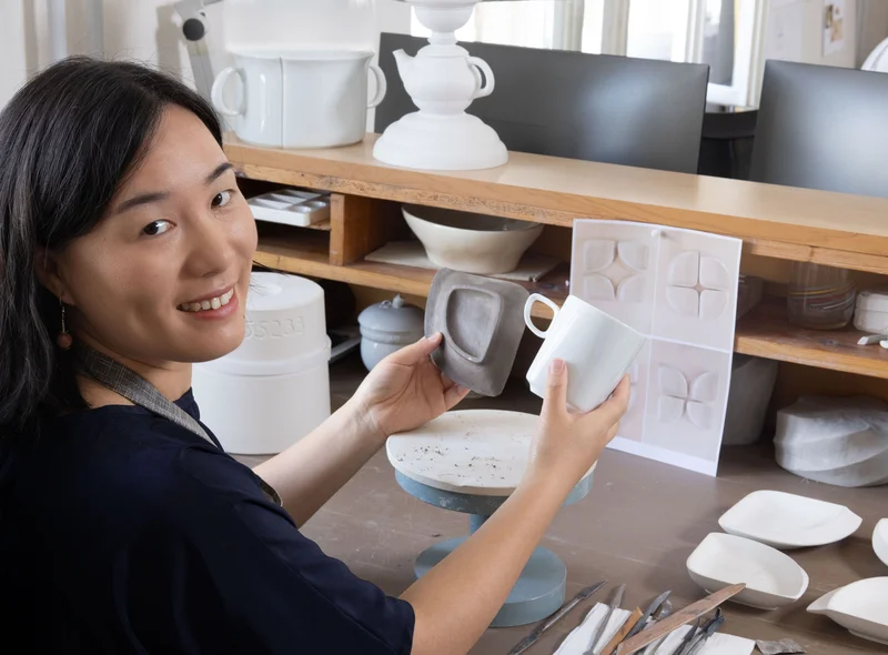 MEISSEN-Porzellan-Designerin Zhuoyu Hou prüft Tassenentwürfe im Atelier – eine ruhige, kreative Arbeitsatmosphäre.