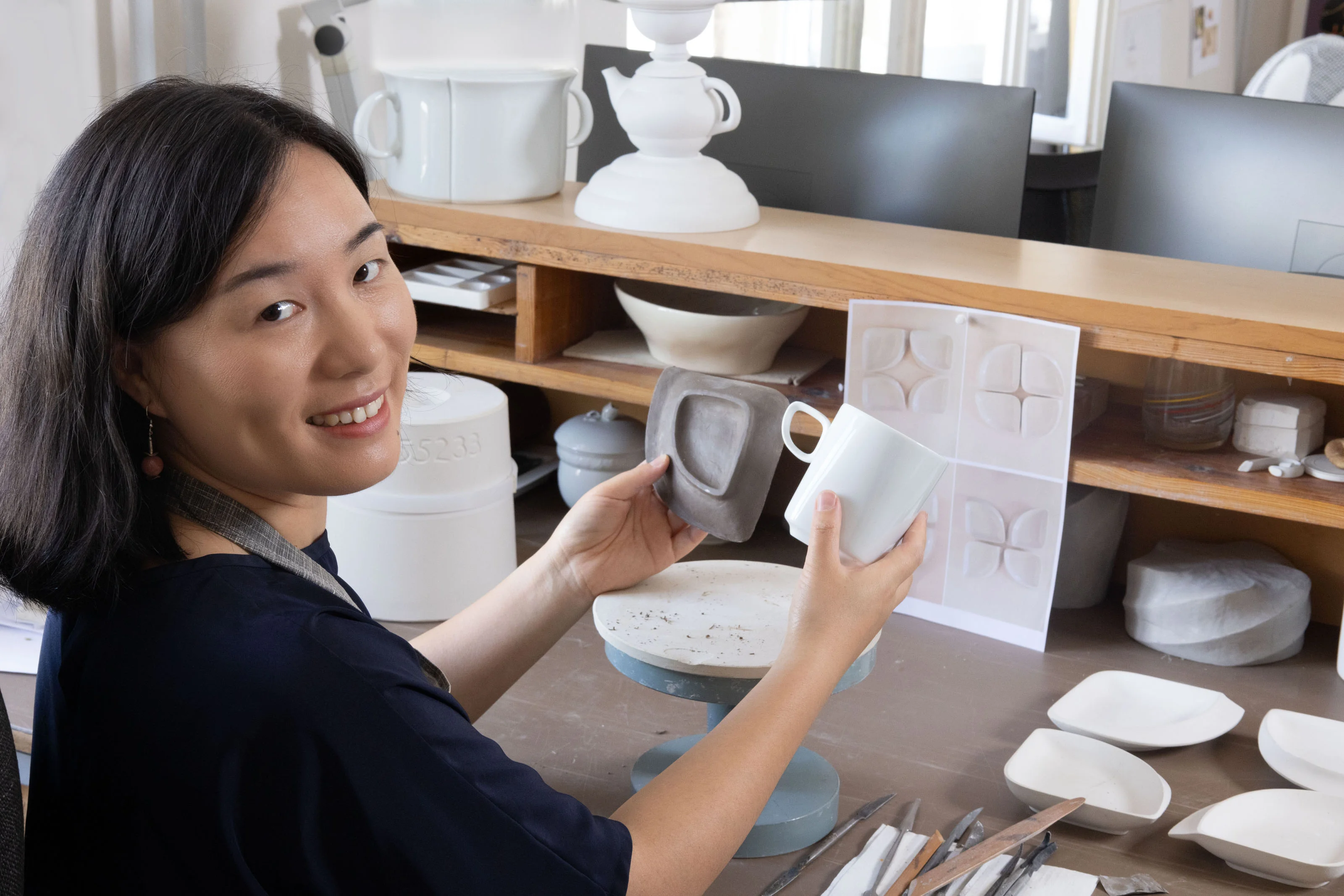MEISSEN-Porzellan-Designerin Zhuoyu Hou prüft Tassenentwürfe im Atelier – eine ruhige, kreative Arbeitsatmosphäre.