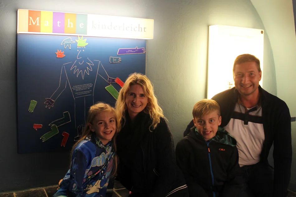 Eine vierköpfige Familie blickt in die Kamera, im Hintergrund ist auf einer Ausstellungswand die Überschrift "Museumsnacht" erkennbar.