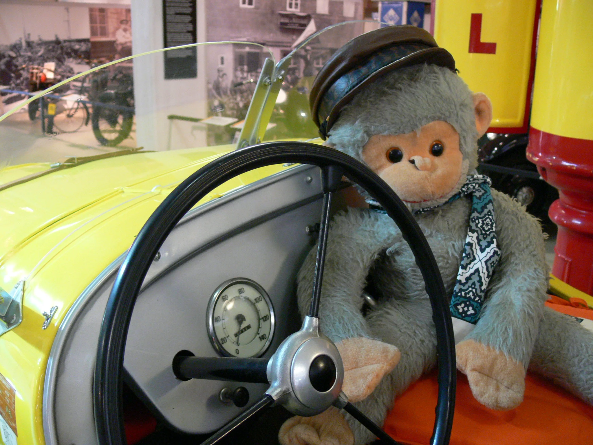 Ein Plüschaffe sitzt neben dem Lenkrad eines historischen Spielautos.