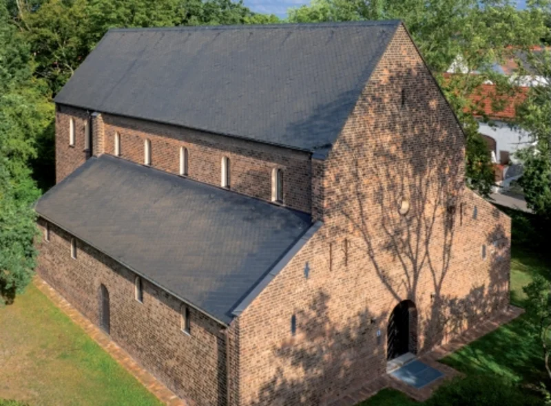 Luftbild eines großen historischen Backsteingebäudes, umgeben von Bäumen