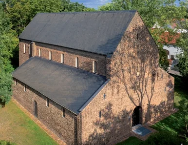 Luftbild eines großen historischen Backsteingebäudes, umgeben von Bäumen