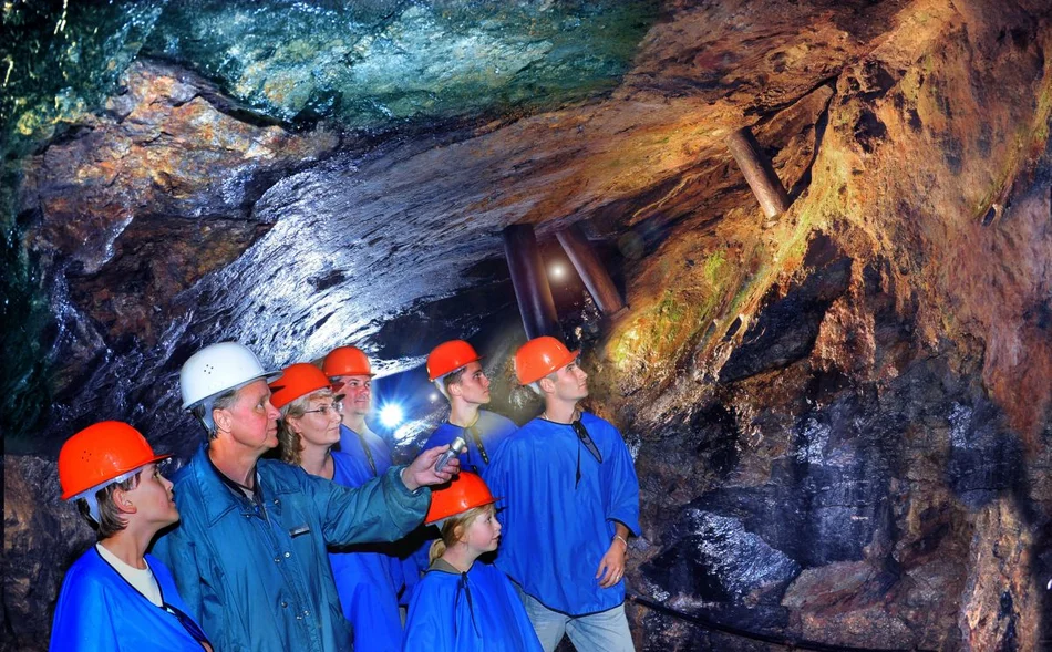 Blick ins Besucherbergwerk Das Foto zeigt mehrere in blaue Kittel und Helme tragende Gäste untertage im Besucherbergwerk „Im Gößner“ des Erzgebirgsmuseums Annaberg-Buchholz.