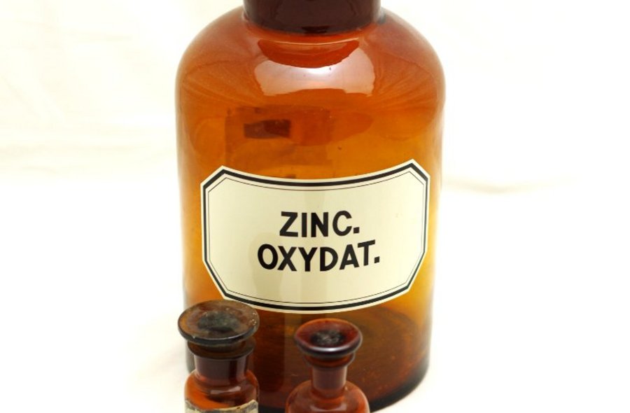 Drei historische Apotheker-Fläschchen aus braunem Glas, die größte ist etikettiert mit den Worten "Zinc Oxydat".