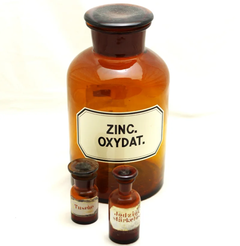 Glasgefäße aus der Löwen-Apotheke Bad Lausick Drei historische Apotheker-Fläschchen aus braunem Glas, die größte ist etikettiert mit den Worten "Zinc Oxydat".